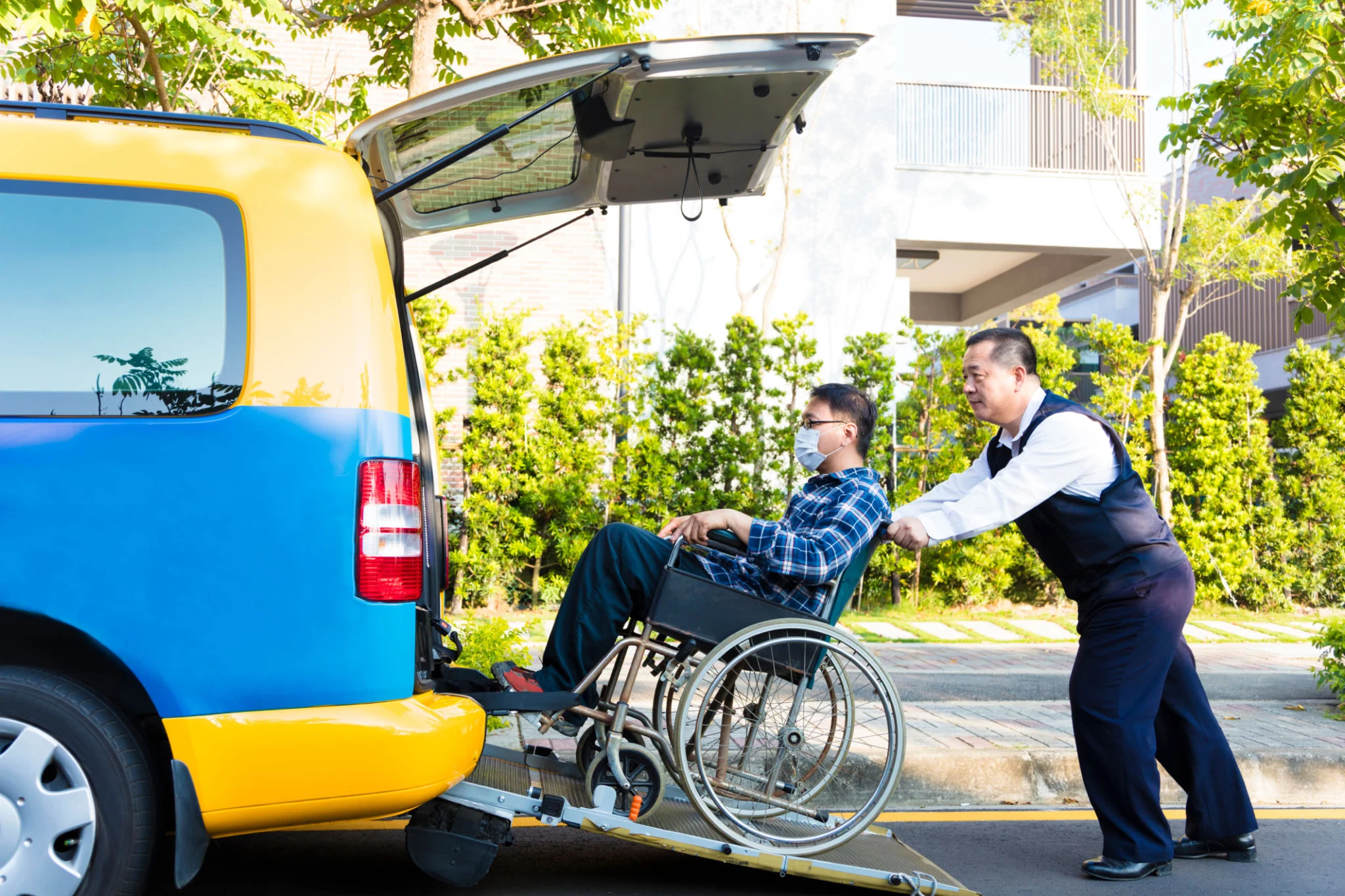 driver helping man on wheelchair getting into taxi